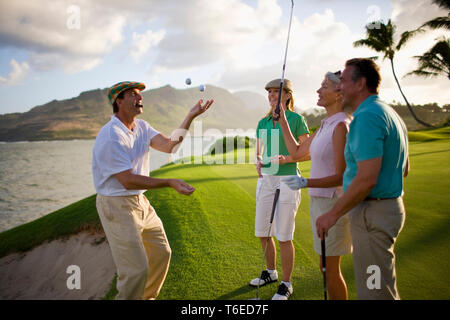 Golfista maschio di fumare un sigaro giocola palline da golf per i suoi amici come si prendono una pausa insieme. Foto Stock