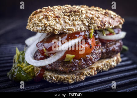 Barbecue Wagyu Hamburger con cipolle e pomodori come close-up su un grillage Foto Stock