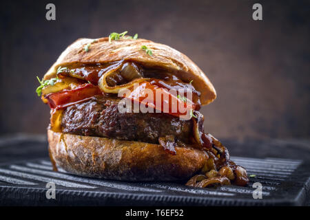 Barbecue Wagyu cheeseburger con cipolle e pomodori come close-up su un grillage Foto Stock