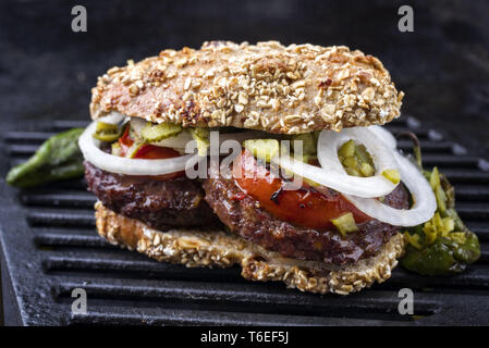 Barbecue Wagyu Hamburger con cipolle e pomodori come close-up su un grillage Foto Stock