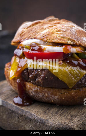 Barbecue Wagyu cheeseburger con cipolle e pomodori come close-up su un tagliere Foto Stock