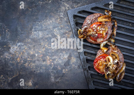 Barbecue Wagyu Hamburger con cipolle e pomodori come vista dall'alto su un grillage con copia spazio a sinistra Foto Stock