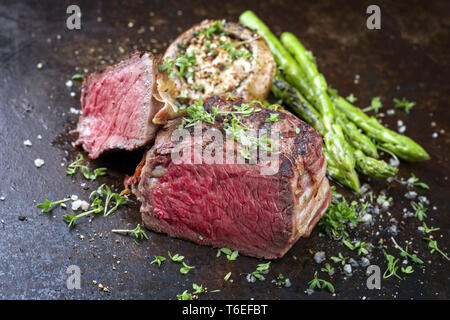 Barbecue punto Wagyu Steak con asparagi verdi e tappo a fungo come close-up su un arrugginito foglio di metallo Foto Stock