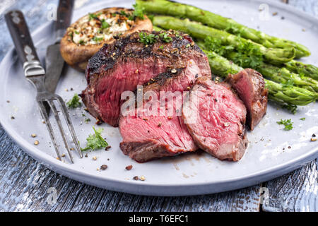 Barbecue punto Wagyu Steak con asparagi verdi e tappo a fungo come close-up su una piastra Foto Stock