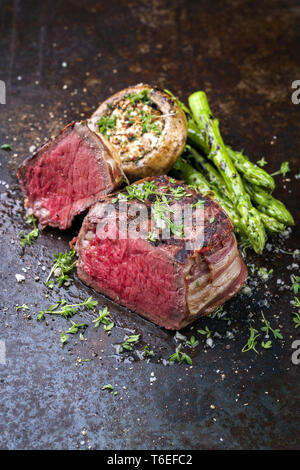 Barbecue punto Wagyu Steak con asparagi verdi e tappo a fungo come close-up su un arrugginito foglio di metallo Foto Stock