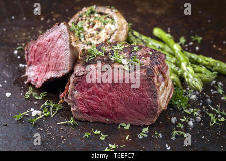 Barbecue punto Wagyu Steak con asparagi verdi e tappo a fungo come close-up su un arrugginito foglio di metallo Foto Stock