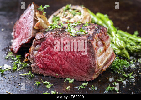 Barbecue punto Wagyu Steak con asparagi verdi e tappo a fungo come close-up su un arrugginito foglio di metallo Foto Stock