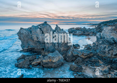 Splendide rocce sulla fascia costiera sull'oceano al tramonto Foto Stock