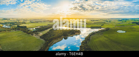 Sun impostazione sulla scenica campagna Australiana le praterie e i pascoli con il fiume passando attraverso - panorama dell'antenna Foto Stock