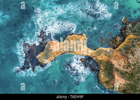 Guardando verso il basso in corrispondenza dell'oceano di onde che si infrangono su rocce erose - vista aerea Foto Stock