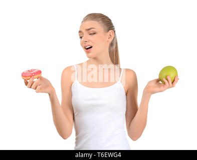 Giovane donna scegliendo tra ciambella e Apple su sfondo bianco. Cucina dietetica concept Foto Stock