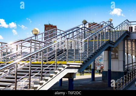 Vista del nuovo case moderne della città di Khabarovsk. Luminoso cielo blu in una giornata di sole. Diagonale ringhiera lucido in primo piano. Foto Stock