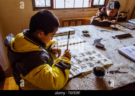 Lijiang, nella provincia dello Yunnan in Cina : Bambini pratica ad una calligrafia tradizionale scuola nella città vecchia di Lijiang, una storica nazionale e culturale Foto Stock