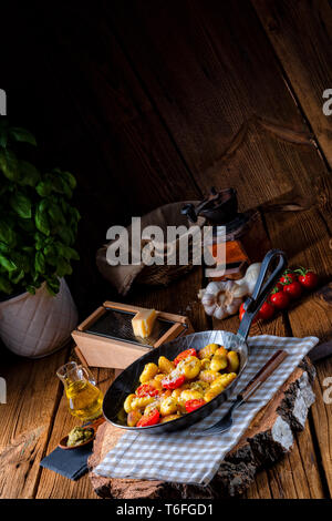 Gnocchi al forno con pesto verde, pomodorini e scaglie di parmigiano Foto Stock