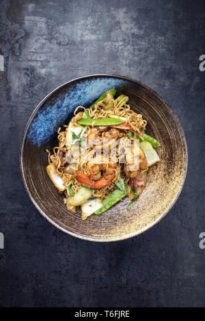 Tradizionale stir-fried Thai phat mama mie tagliatelle con gamberoni e verdure come vista dall'alto in una ciotola Foto Stock