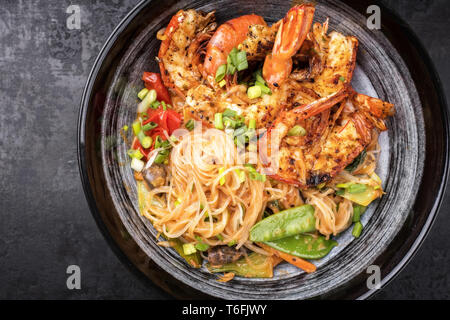 Tailandese tradizionale Phak Kung curry con barbecue gamberoni e tagliatelle come vista dall'alto in una ciotola Foto Stock