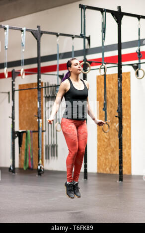 Giovane donna che lavora fuori con una corda da salto in una palestra professionale in una lunghezza piena vista in una salute e concetto di fitness Foto Stock