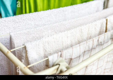 Bianche e colorate lenzuola e asciugamani per essere essiccato sul stendibiancheria. Foto Stock