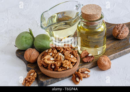 Olio di noce in una bottiglia e un bicchiere di vetro. Foto Stock