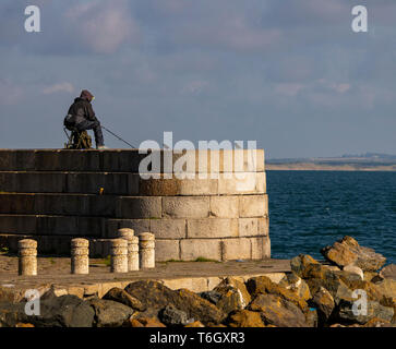 Un maschio solitario pesca al largo molo Foto Stock