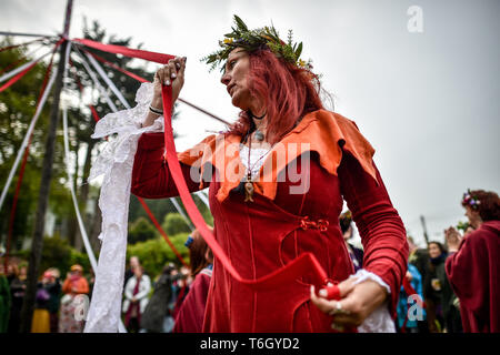 Una donna guarda al suo nastro come persone danza attorno al maypole durante le celebrazioni di Beltane a Glastonbury calice e in cui le persone si radunano per osservare una moderna interpretazione della antica pagana celtica rito di fertilità della molla. Foto Stock