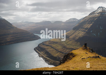 Due escursionisti sulla cima di una montagna vicino a Funningur con vedute spettacolari della Scenic fiordi sulle Isole Faerøer (Isole Faerøer, Danimarca, Europa) Foto Stock