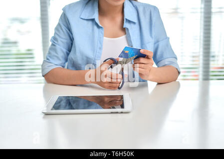 Shopping femmina il taglio la sua carta di credito con le forbici Foto Stock