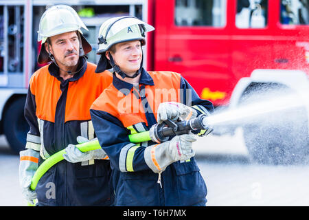Gli uomini dei vigili del fuoco di spegnere un incendio Foto Stock