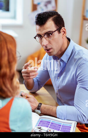 Bel giovane serio che spiega la regola Foto Stock