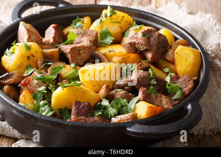 Patate fritte con carne e funghi vicino sul tavolo, stile rustico. orizzontale Foto Stock