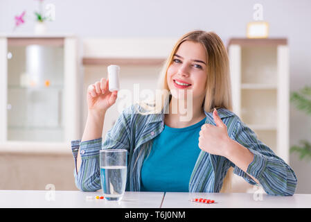 Donna di prendere le pillole per affrontare il dolore Foto Stock