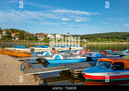 La città e il benessere di Schluchsee visto dalla riva del lago con barche a noleggio per i turisti, Alta Foresta Nera, Germania, attrazione turistica Foto Stock