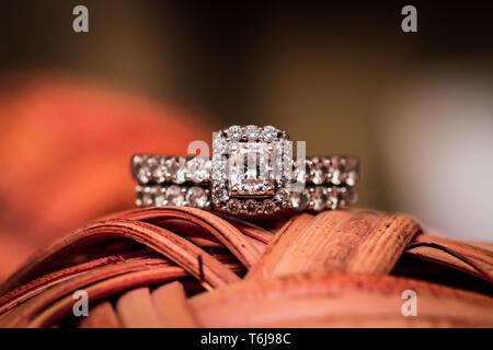 Ripresa macro di un diamante anello nuziale sulla parte superiore di un oggetto rosso con un bellissimo sfondo bokeh di fondo. Foto Stock