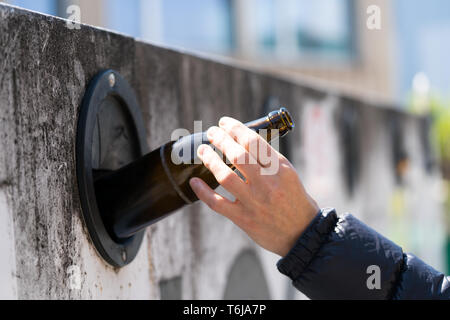 Vista in dettaglio di una femmina di mano il vetro di riciclo per salvare l ambiente presso il suo locale di impianti di riciclaggio Foto Stock