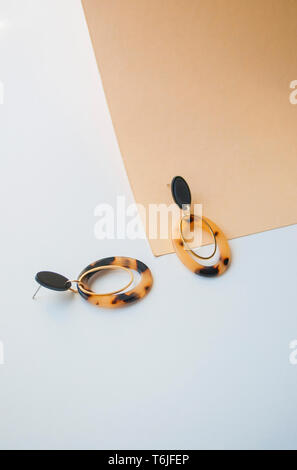 Orecchini con leopard stampa su beige e marrone colore sfondo con copyspace. Foto Stock