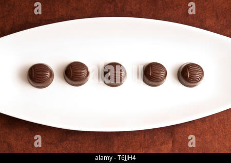 Fila di Bonbons di cioccolato su un bianco piastra di porcellana Foto Stock