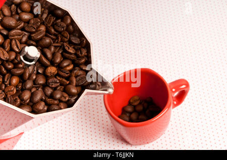 Red caffettiera moka e rosso coppa piena di chicchi di caffè Foto Stock