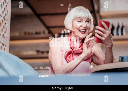 Emozionato old Lady con bob haircut osservando un messaggio ricevuto Foto Stock