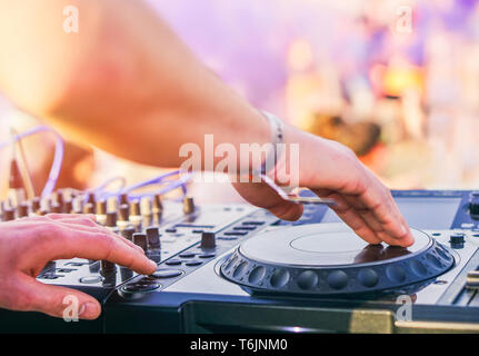 Il mixaggio DJ presso il beach party festival con la gente ballare in background - Deejay riproduzione di musica mixer audio esterni - Concetto di eventi estivi