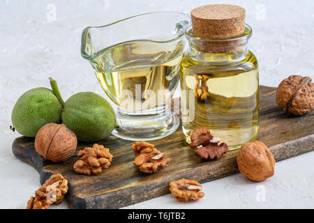 Olio di noce in una bottiglia e un bicchiere di vetro. Foto Stock