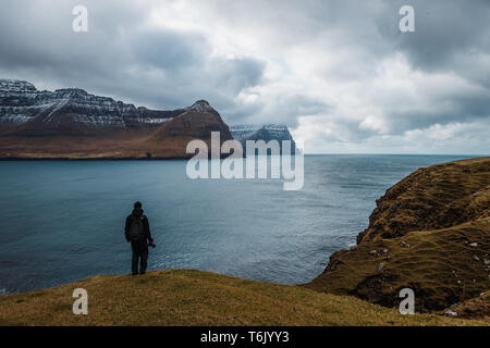 Fotografo godendo della vista di Kunoy e isola di Kalsoy come visto da Kap Enniberg in Viðareiði (Isole Faerøer, Danimarca, Europa) Foto Stock