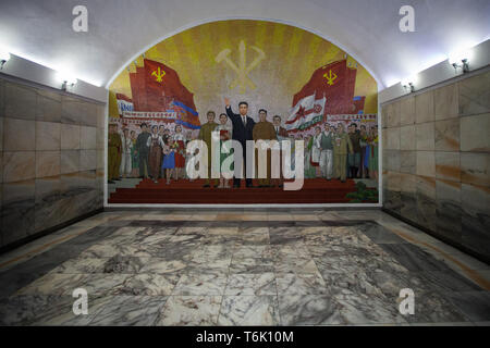 Un grande mosaico murale all'interno di un regime di Pyongyang stazione metropolitana mostra le bandiere e dei lavoratori e il simbolo della Corea del Nord di partito comunista. Foto Stock