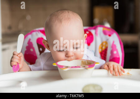 Il bambino è di 8 mesi e si mangia in modo indipendente.Il primo richiamo bambino.il bambino con gli occhi blu non vuole mangiare la purea di verdure.mom feed da un piccolo bambino' Foto Stock