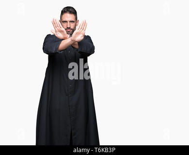 Giovane sacerdote cristiano su sfondo isolato rifiuto espressione bracci di attraversamento e di palme facendo segno negativo, volto arrabbiato Foto Stock