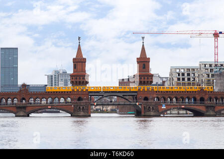 Vecchie gialle U-Bahn metropolitana treno attraversando il famoso Ponte Oberbaum (Oberbaumbrucke) oltre il fiume Sprea a Berlino, Germania. Foto Stock