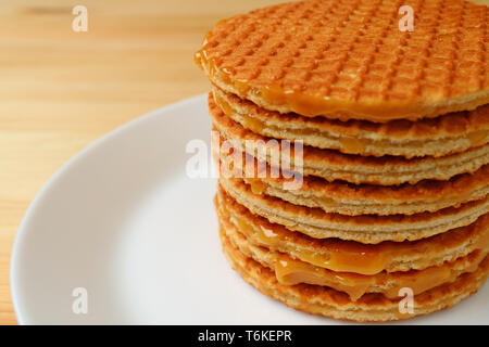 Pila di succulenti Stroopwafels sulla piastra bianca servita su un tavolo di legno Foto Stock