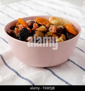 Frutta secca e noci in una ciotola rosa, vista laterale. Primo piano. Foto Stock