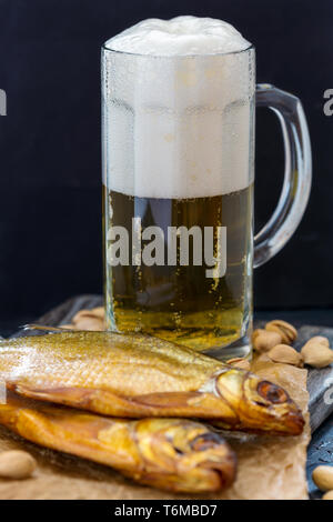 Bicchiere di birra, pesce affumicato e pistacchi. Foto Stock