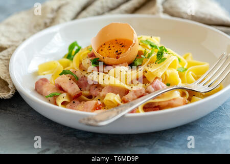 La pasta alla carbonara con tuorlo d'uovo e la forcella nella piastra. Foto Stock