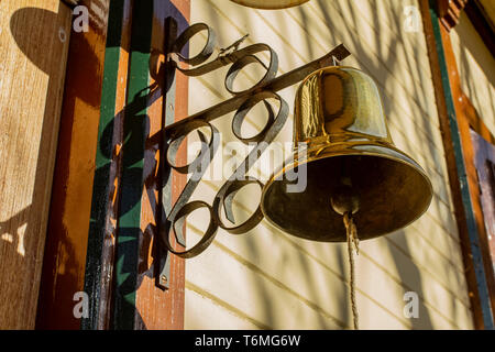 Vecchio vintage campana in bronzo su una vecchia casa in legno. Foto Stock